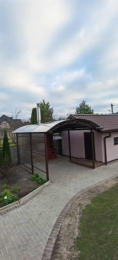 Полукруглый навес из поликарбоната у стены дома