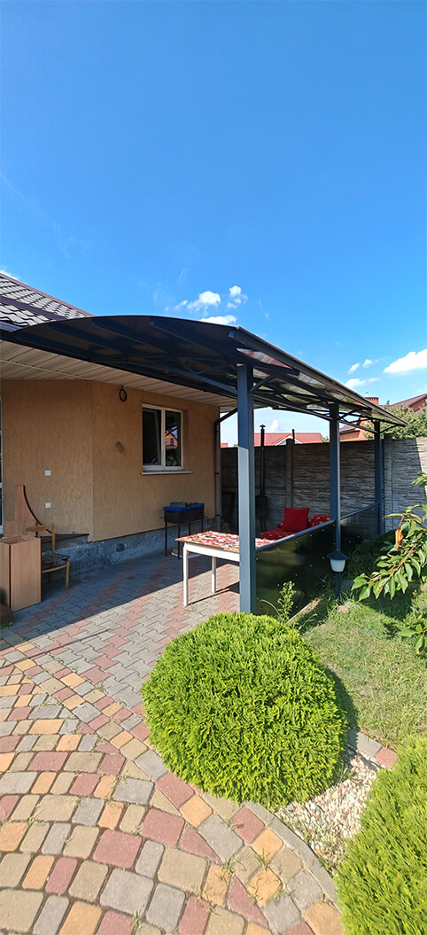 Полукруглый навес из поликарбоната у стены дома для стола