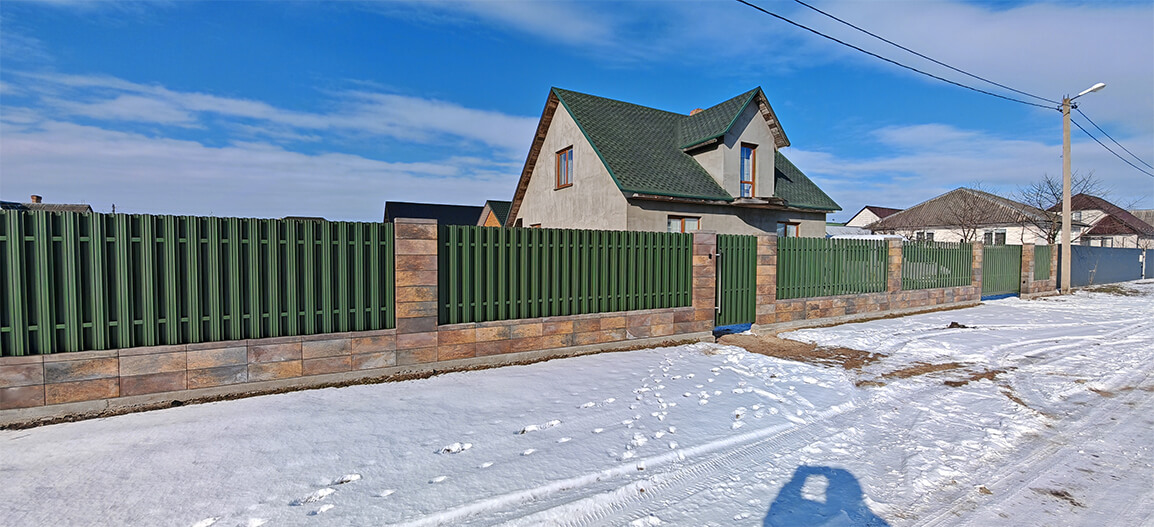 Забор из металлического штакетника зелёный на кирпиче