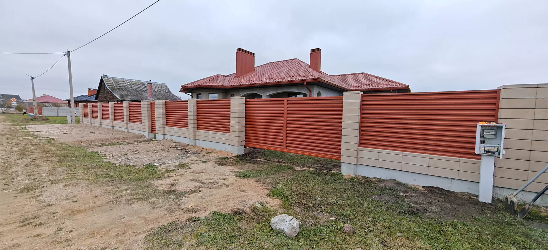 Красный забор-жалюзи с калиткой на бежевых столбах из плитки