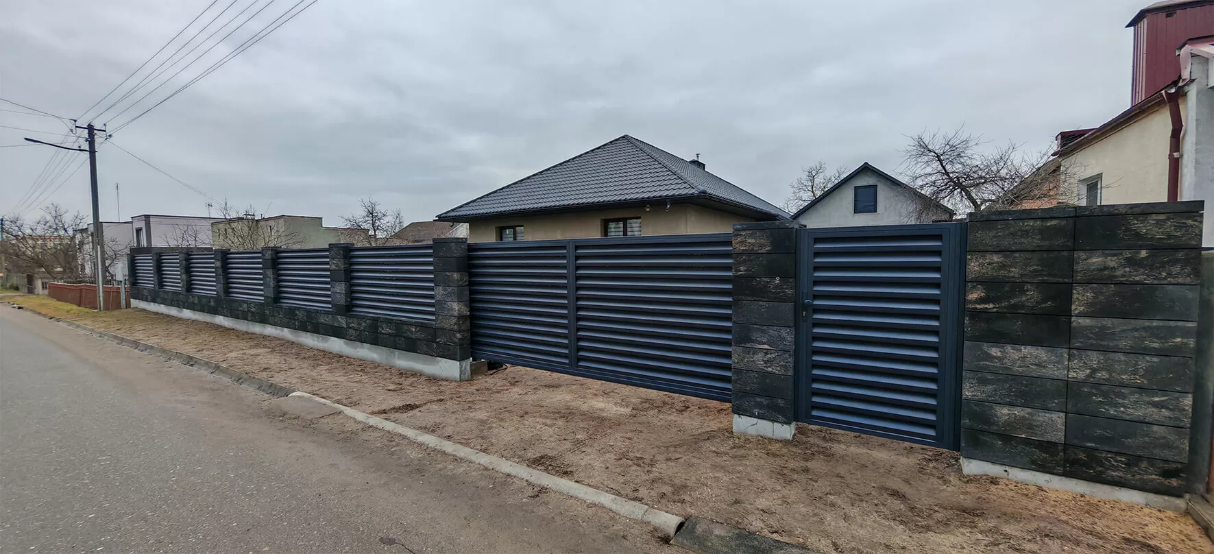 Забор-жалюзи чёрного цвета на столбах из тёмного камня